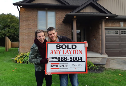 A couple standing outside of their newly sold home