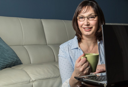 Amy Layton sitting in front of her couch with a laptop in front of her